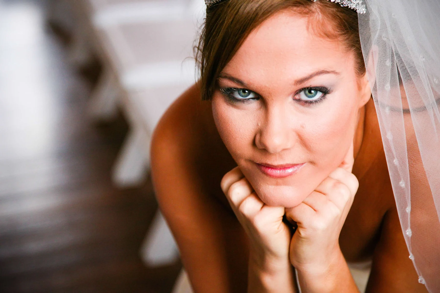 A bride resting her chin on her hands, with makeup by Rockelle